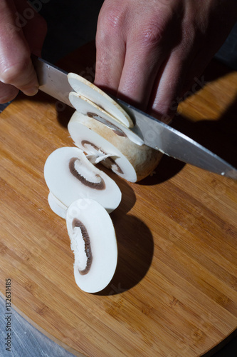 Mano de cocinero cortando a láminas un champiñón