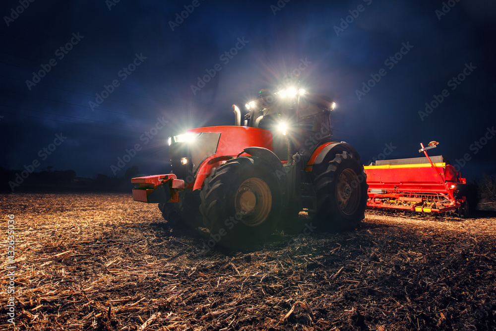 Fototapeta premium Tractor preparing land with seedbed cultivator at night