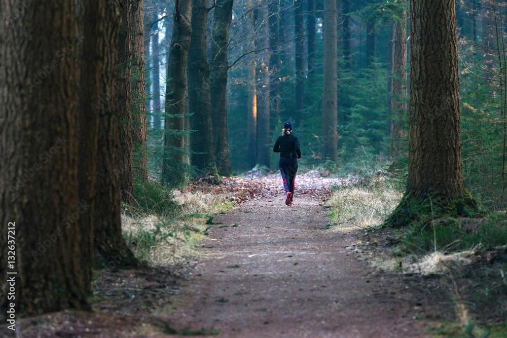Woman running on path in winter pine forest. Rear view. Woman running on path in winter pine forest. Rear view.