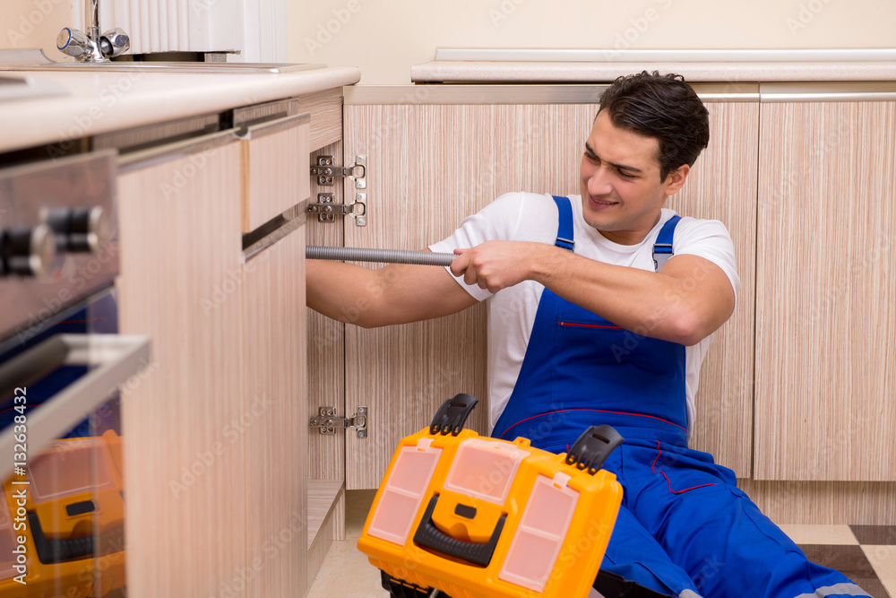 Young repairman working at the kitchen Young repairman working at the kitchen