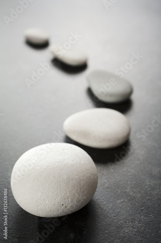 Canvas Print Curving Line of Grey Pebbles on Dark Background