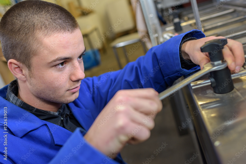 Fototapeta premium Young man using spanner
