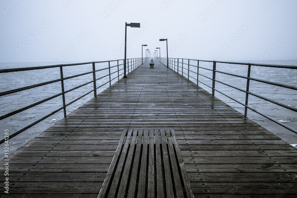 Pier In The Fog. Long pier diminishing into the foggy Great Lakes Horizon. Harbor Beach, Michigan.