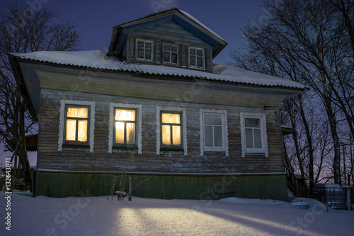 Canvas Print Warm light from windows ofcozy old russian village house in the bitter cold