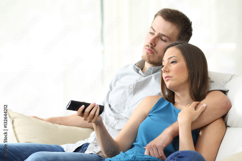 Couple bored watching tv at home Couple bored watching tv at home