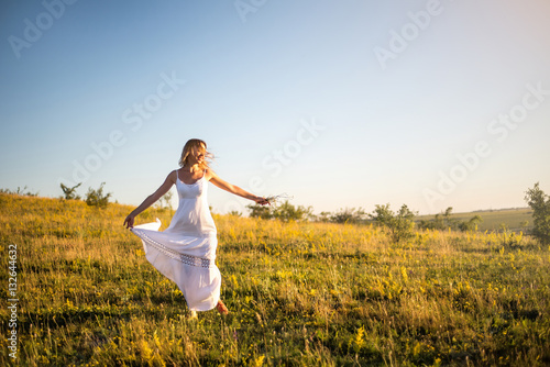 Young romantic woman on the meadow at sunset. The girl in the wh