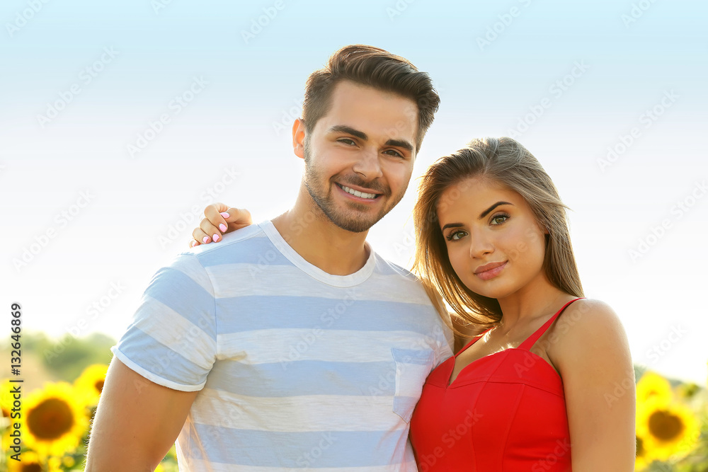 Obraz premium Happy young couple in a field of sunflowers
