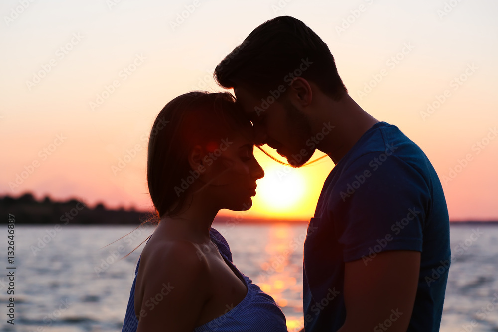 Young couple kissing on the beach at sunset