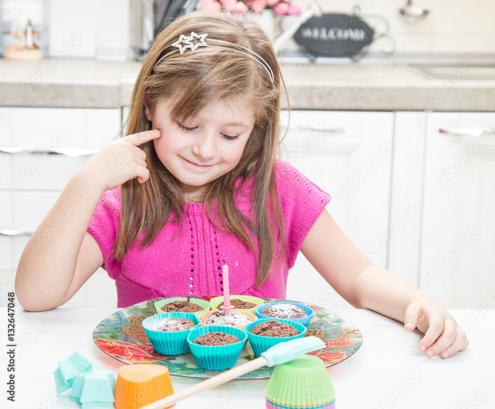 bambina felice che spegne la candelina di compleanno su torta di muffin  Stock-Foto