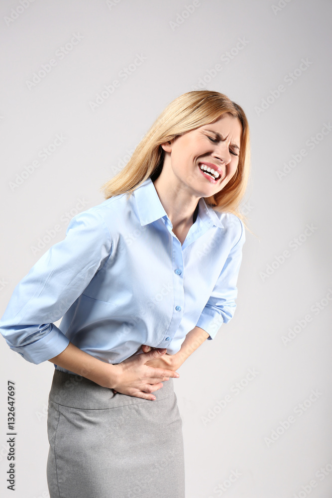 Young woman suffering from pain on grey background Young woman suffering from pain on grey background