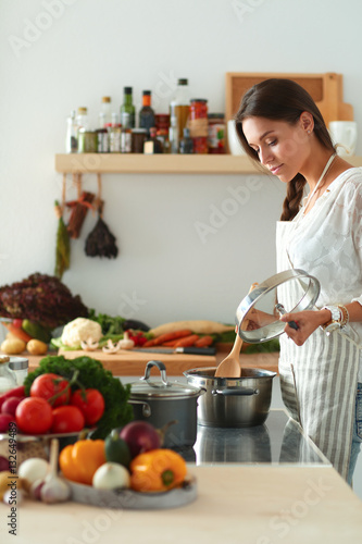 Young woman standing by the stove in the kitchen