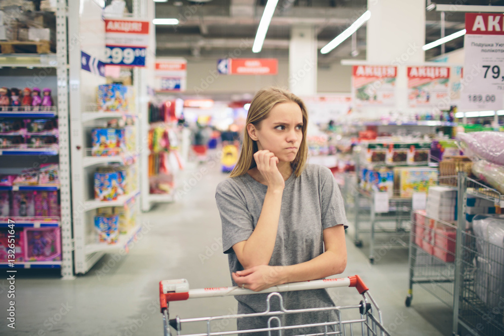 Curious Woman in The Supermarket . Young girl in a market store with  shopping thinking what to buy