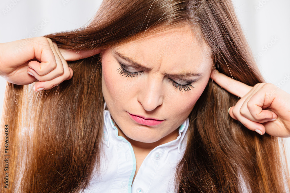 Fototapeta premium Stressed woman with closed eyes put fingers in ears,