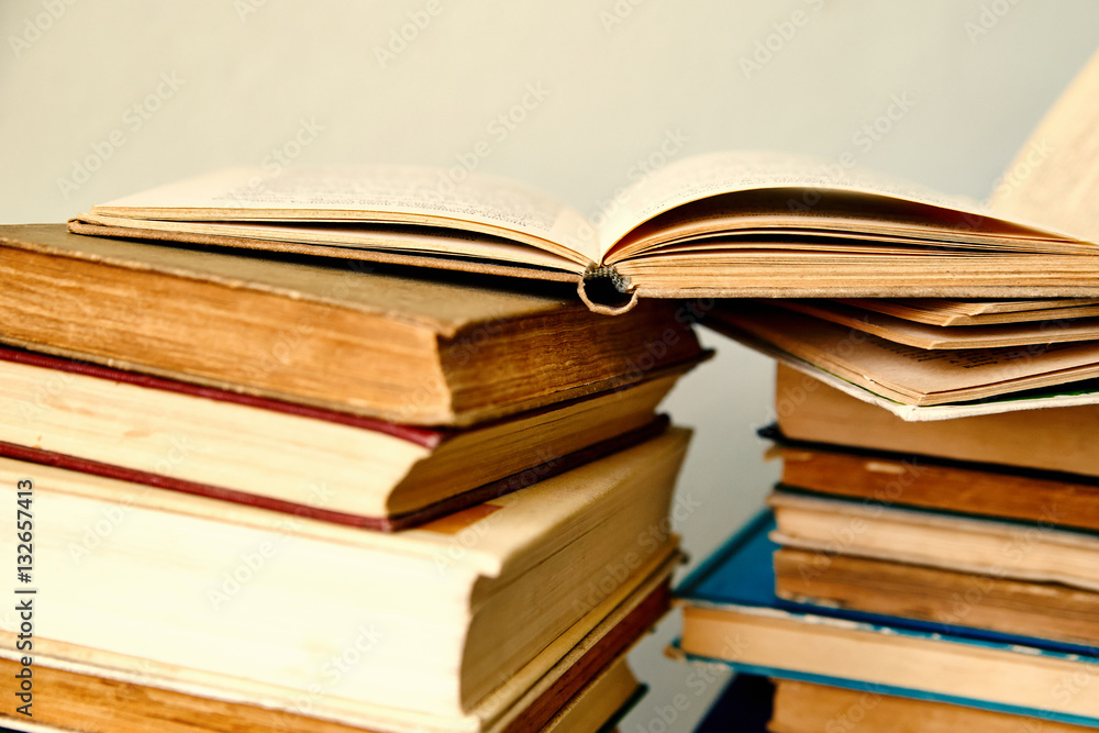 pile of old books and an open book in hardcover pile of old books and an open book in hardcover