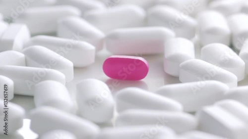 Pink pill isolated surrounded by white pills photo