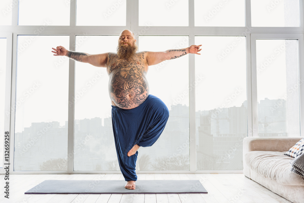 Tattooed man practicing yoga at home - obrazy, fototapety, plakaty 