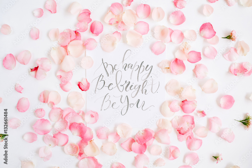 Be bright. Be happy. Be you. Inspirational quote made with calligraphy and floral pattern with pink rose petals. Flat lay, top view