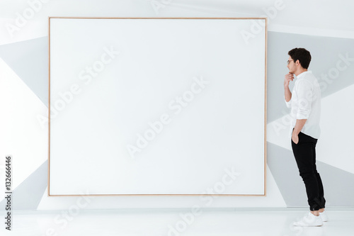 Handsome man standing near big board. © Drobot Dean