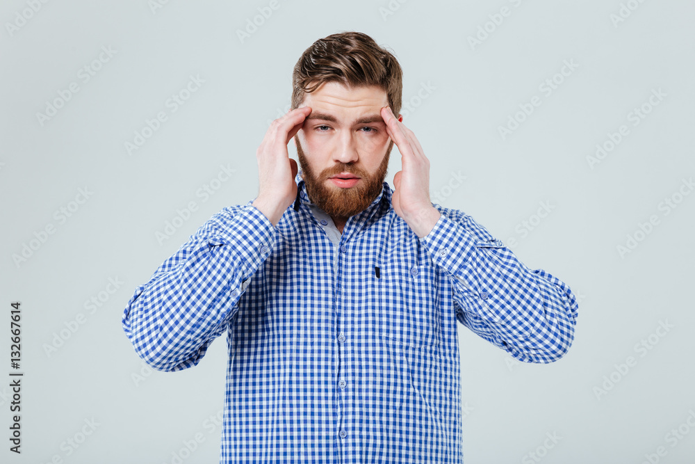 Upset depressed young man touching his temples and having headache Upset depressed young man touching his temples and having headache