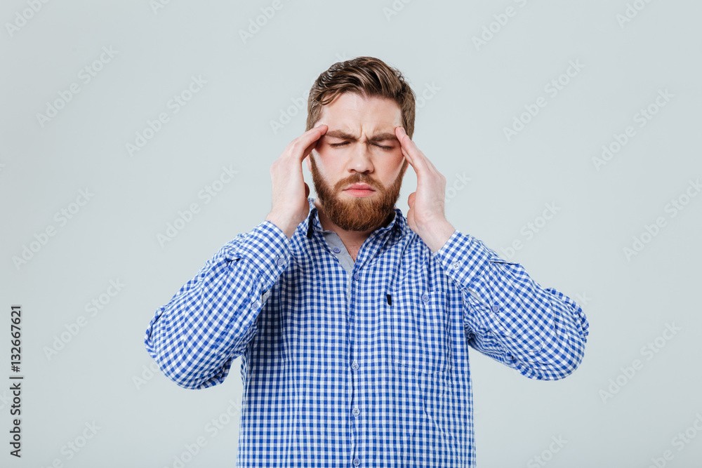 Tensed bearded young man touching his temples and having headache Tensed bearded young man touching his temples and having headache