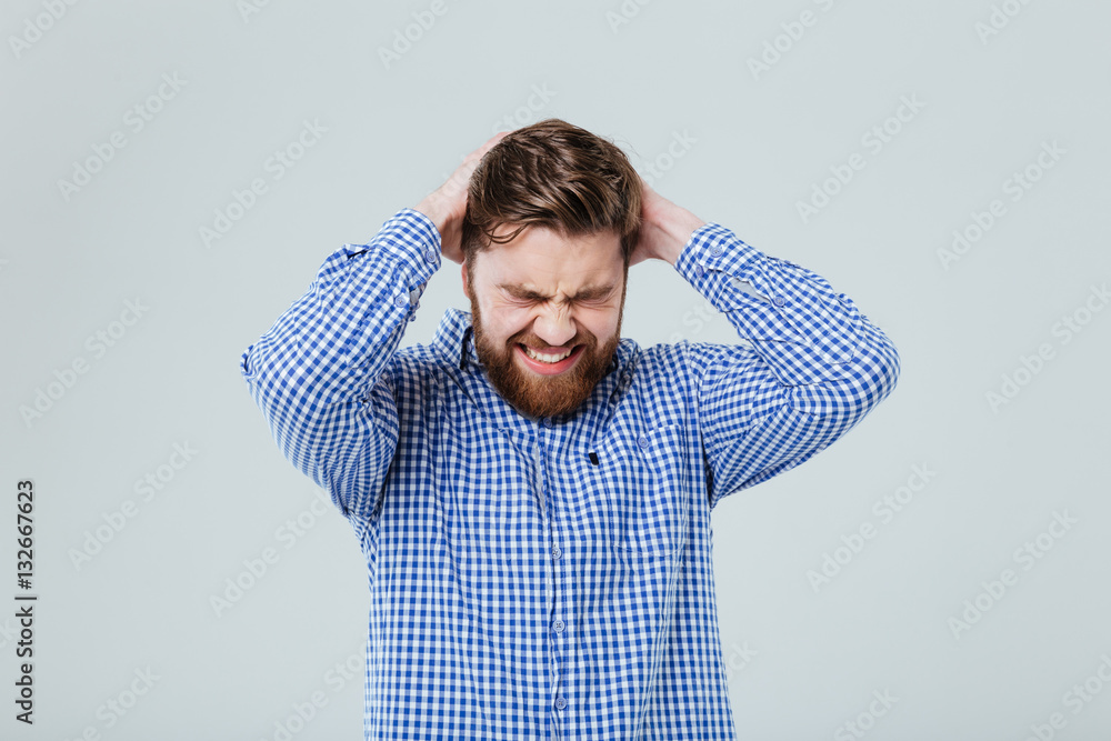 Stressed bearded young man with closed eyes having headahce Stressed bearded young man with closed eyes having headahce