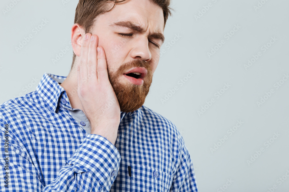 Stressed bearded young man suffering from toothache Stressed bearded young man suffering from toothache
