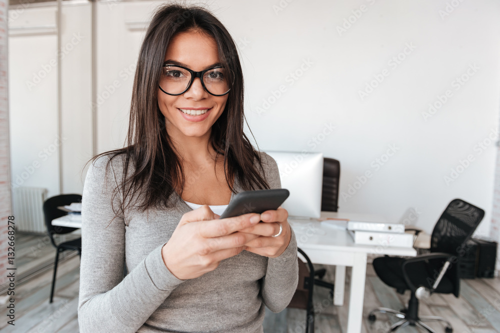 Smiling lady wearing eyeglasses in office using telephone Smiling lady wearing eyeglasses in office using telephone