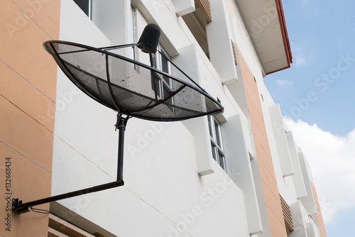 Black satellite dish at the building wall photo