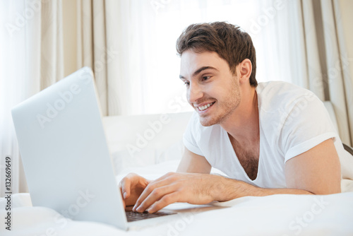 Happy man using laptop on bed © Drobot Dean