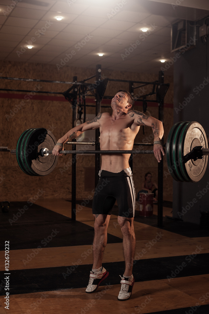 Fototapeta premium Strong muscular man lifting barbell in gym