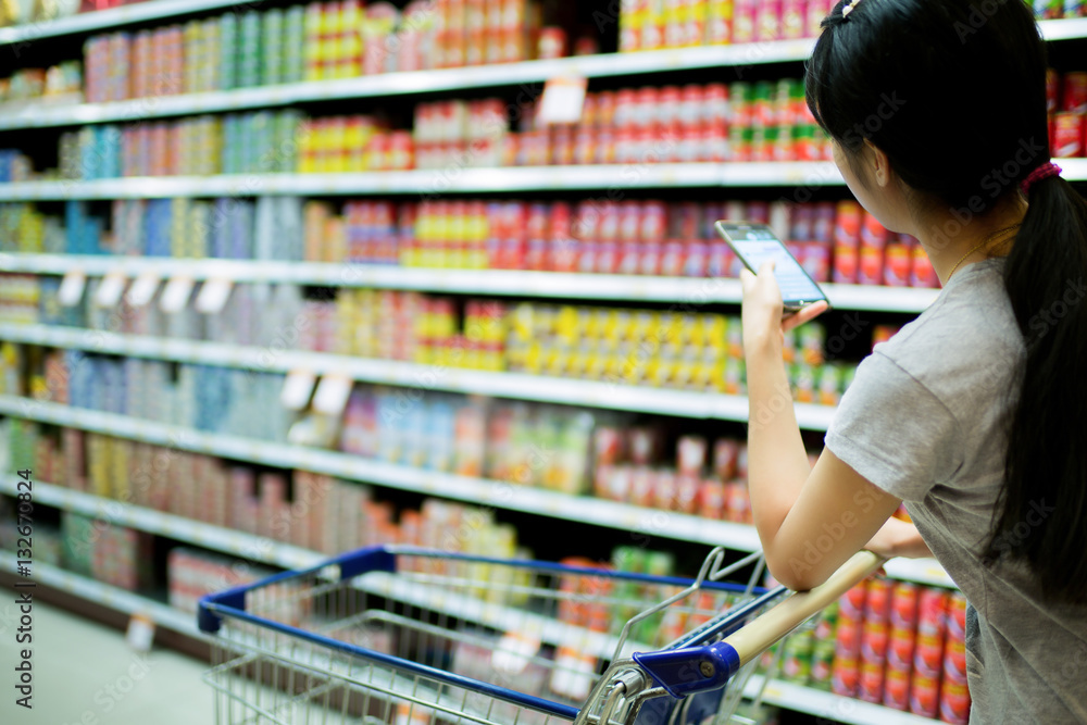 Woman using phone in supermarkets check to buy