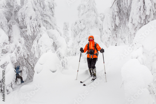 man alone traveling on skis in the snowy winter woods, adventure and recreation concept