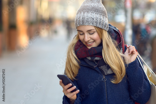 Modische junge Frau mit Einkaufstaschen und Handy 