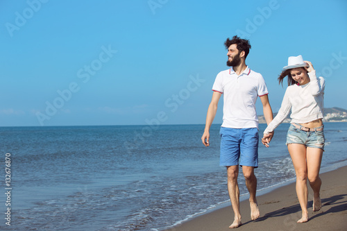 Couple walking on beach. Young happy interracial couple walking on beach smiling holding around each other. © FS-Stock