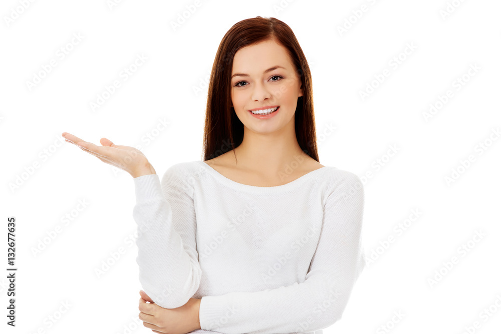 Smiling young woman presenting something on open palm Smiling young woman presenting something on open palm