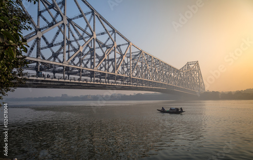 Howrah bridge Kolkata at dawn with wooden boat on river Hooghly.