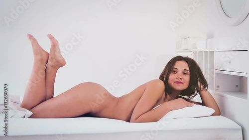 Young seductive woman with naked body lounging in bedroom photo