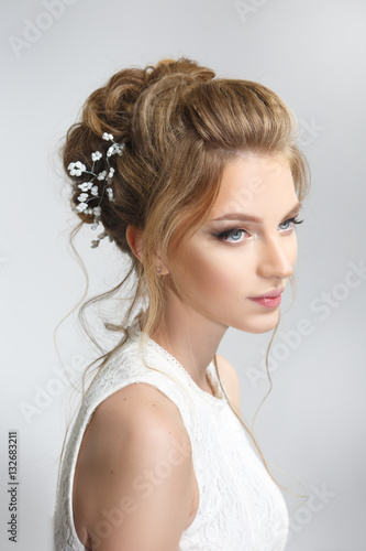 Pretty bride with beautiful elegant hairstyle, isolated on a gray background.