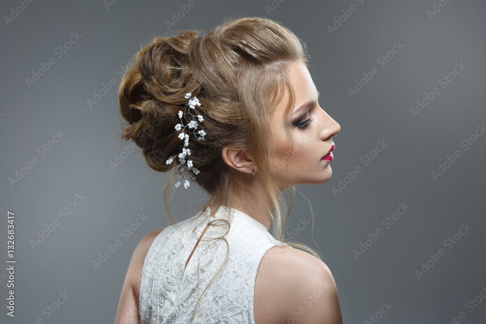 Fototapeta Elegant bride with a beautiful hairstyle and bright make-up isolated on a gray background.