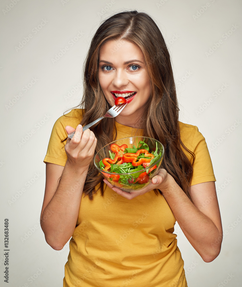 smiling woman eatin vegatable salad with fork.