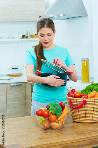 Young woman standing in kitchen cooking food.