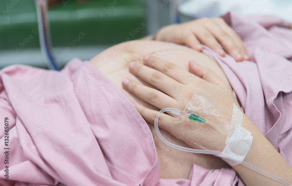Fototapeta premium Close up of pregnant woman with IV solution in delivery room