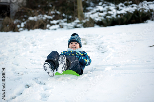 Fotografie Cute child, boy, sliding with bob in the snow, wintertime