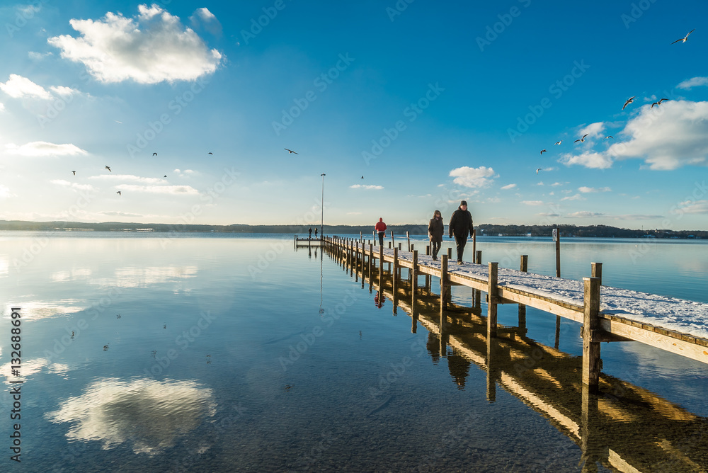 Menschen und Möwen am Holzsteg am Starnberger See im Winter