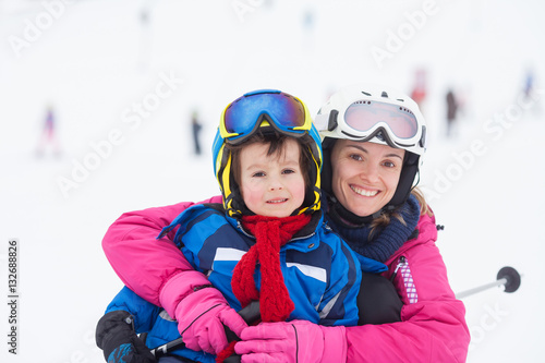 Sweet young boy and his mother, learning to ski on a mild ski sl