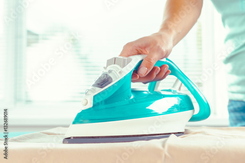 Closeup of woman ironing clothes on ironing board