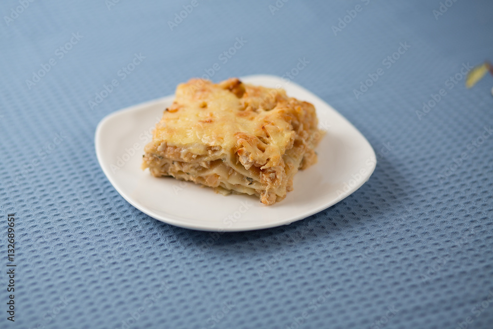 Lasagna with greens on a plate on a blue napkin, macaroni with chicken forcemeat