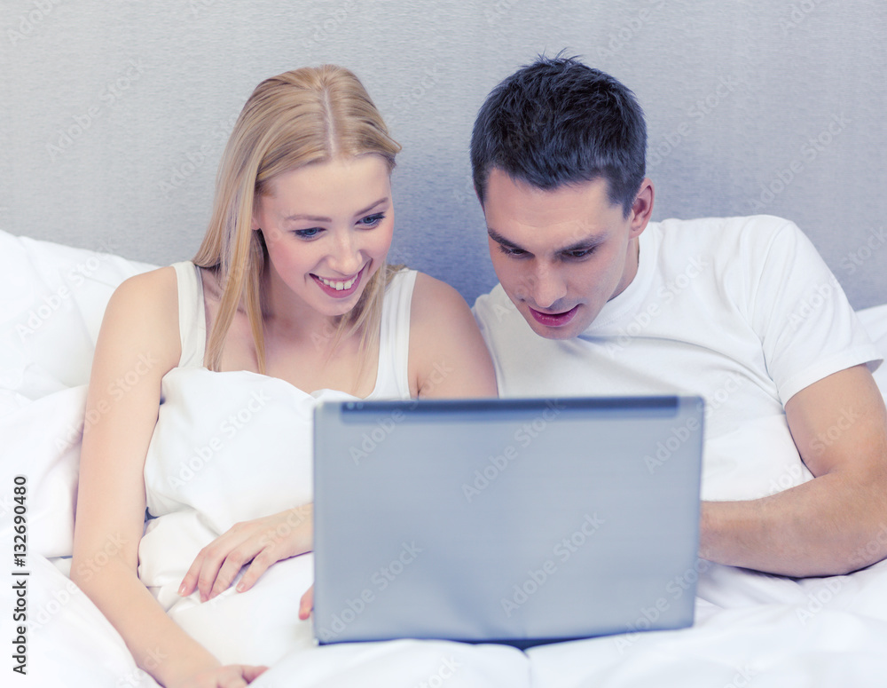 smiling couple in bed with laptop computer smiling couple in bed with laptop computer