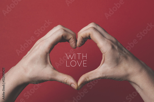 Female hands creating the shape of a love heart around a romantic message.