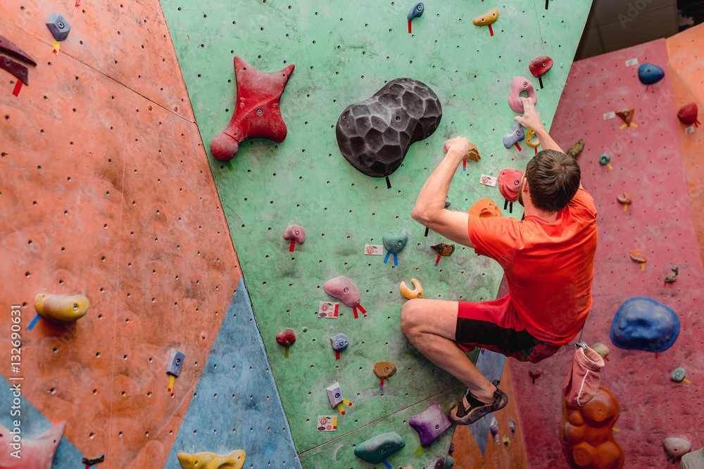 Obraz premium Sport man exercising on artificial climbing wall, modern leisure concept